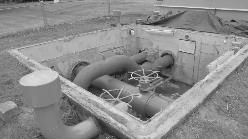 A valve chamber with large pipes and hand wheels