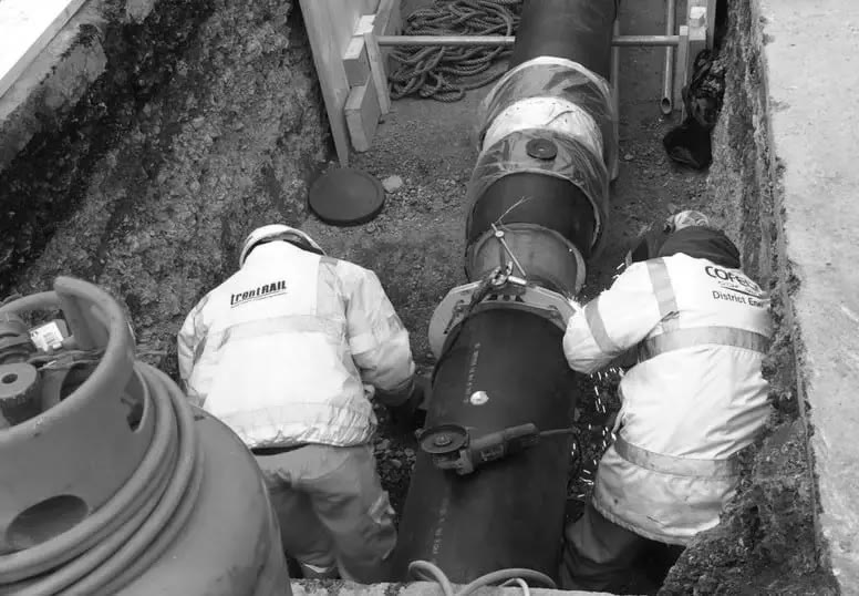 Workers joining district heating pipes in a trench